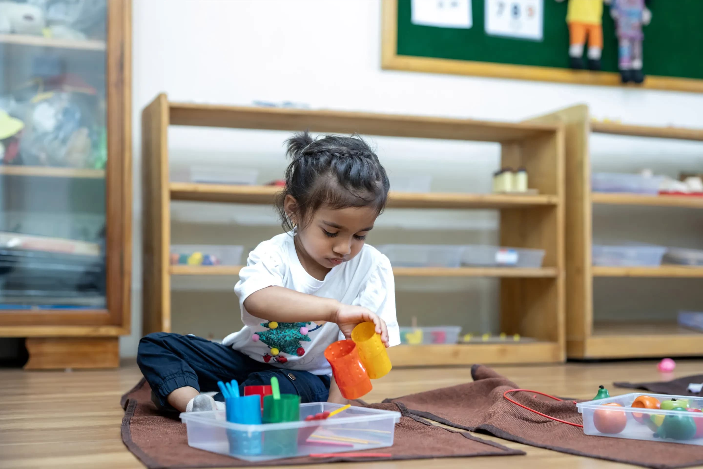 Child focusing on Montessori cylinders